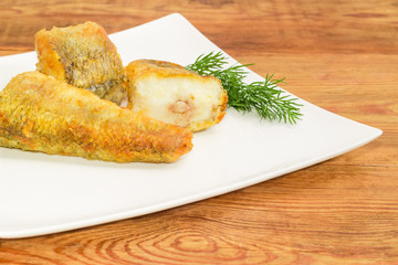 Slices of the fried fish and dill on dish closeup