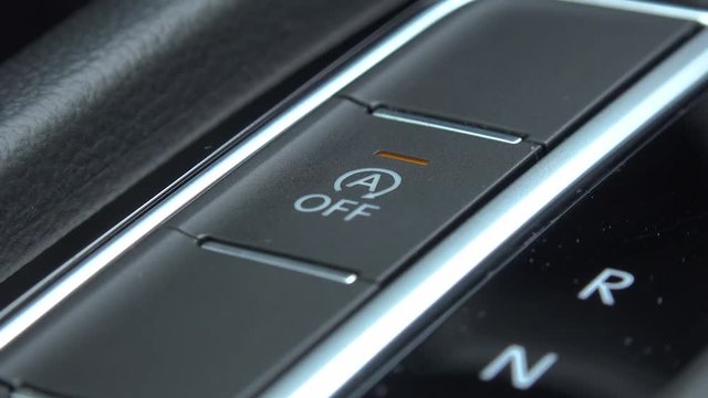 A woman presses an Auto Start-Stop button in a car - closeup