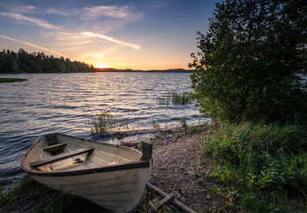 Scenic landscape with idyllic lake view and boat at summer evening in Finland