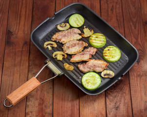 Grilled streaky bacon, vegetable marrows and mushrooms on grill pan