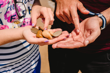 Hands of a couple shining stones on the beach