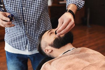 Professional barber working with client in hairdressing salon