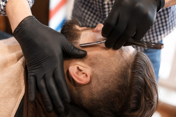 Professional barber working with client in hairdressing salon