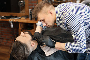 Professional barber working with client in hairdressing salon