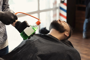 Professional barber working with client in hairdressing salon