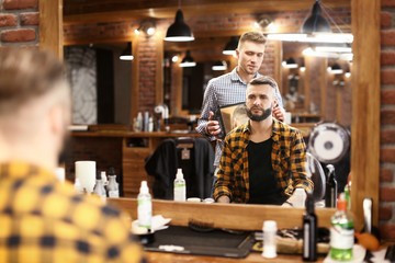Professional barber working with client in hairdressing salon