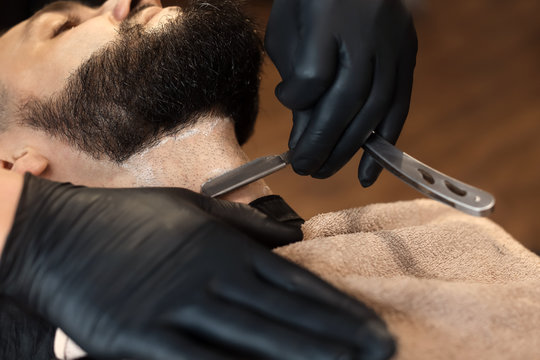 Professional barber working with client in hairdressing salon