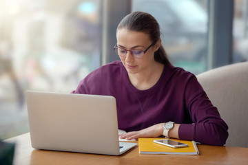 Young freelancer with laptop working in cafe