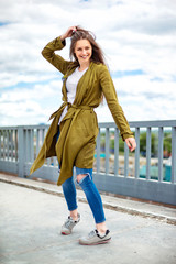 Young stylish girl is having fun outdoors dancing at city background.