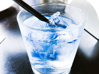 A glass of drinking water filled with ice on the wooden table