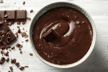 Bowl with molten chocolate on wooden background