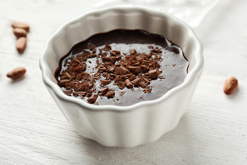Bowl with molten chocolate on wooden background