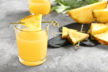 Glass of sweet juice with pineapple slice on table