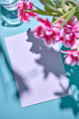 Beautiful spring frame with tulips and white sheet paper on a blue background. Valentine's Day, wedding greeting card.