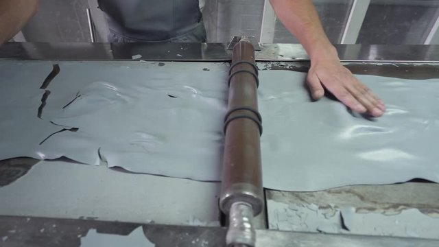 Production of powder paint, worker behind the machine, grinds hard material onto particles.
