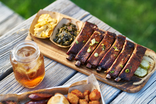 st louis style bbq ribs with collard greens and mac & cheese outside on picnic table during sunny summer day