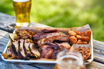  dienblad met gerookt vlees Texas bbq-stijl buiten op picknicktafel op zonnige zomerdag © Joshua Resnick