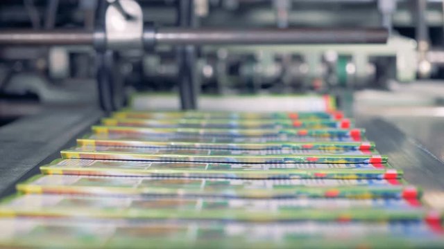 Magazines go on a line out of printing machine, close up.