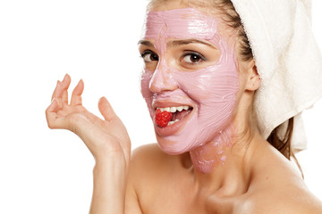 young smiling woman posing with  facial fruit  mask on her face , and with raspberry on her mouth