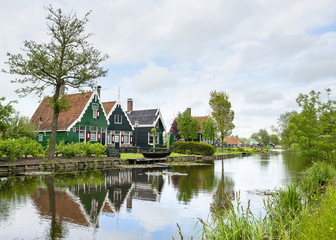 Pitoresque old dutch houses with clouded sky and a river in characteristic dutch landscape