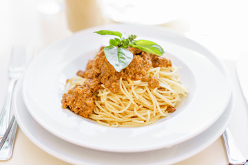 Young happy woman sitting at the table in cafe and enjoying the meal. Hungry woman eating tasty pasta. Dish of spaghetti Bolognese