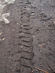 Bike, tractor, excavator, car, automotive tire tracks on muddy trail. Mud and wheel trace on road after rain. Mud with truck wheel track in rainy day. Background, texture, material, wallpaper.