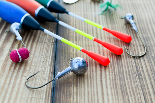 Composition with accessories for fishing on a wooden background. Fishing tackle - floats, hooks, wobblers and baits on a wooden background.