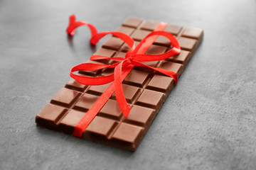 Chocolate bar with color ribbon on grey background