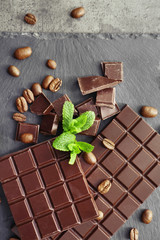 Tasty dark chocolate and coffee beans on table