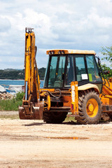Yellow excavator, bulldozer machine and worker tractor. Road works. Road machinery at construction site. Road company and building machines for construction. Industry, renovation and infrastructure.