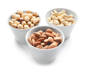 Different nuts in bowls on white background