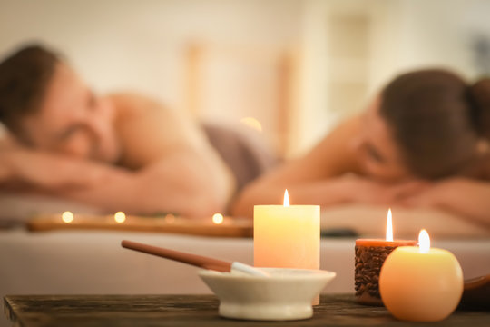 Spa composition with candles and relaxing couple on background