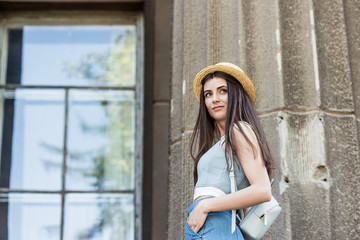 side view of young beautiful woman in straw hat on street