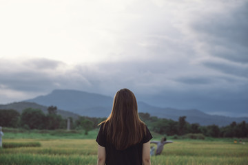 A woman standing and looking at a beautiful rice field onward with feeling relaxed and calm