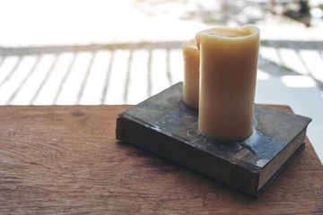 Book and candles on wooden table in cafe