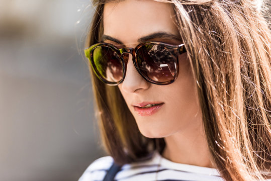portrait of of beautiful young woman in sunglasses on street
