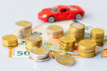 Euro coins in pile on Euro banknotes with red car, financing concept. Germany