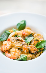 delicious spicy spaghetti seafood dried chilli and basil sauce with shrimp squid and mussel , spicy spaghetti seafood on white plate