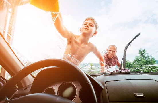 Son helps his father to wash a car