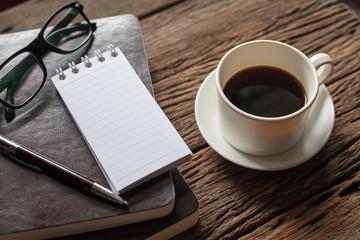 Blank paper with pen and cup of coffee on wooden table