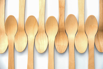 Wooden biodegradable spoons aligned on white background