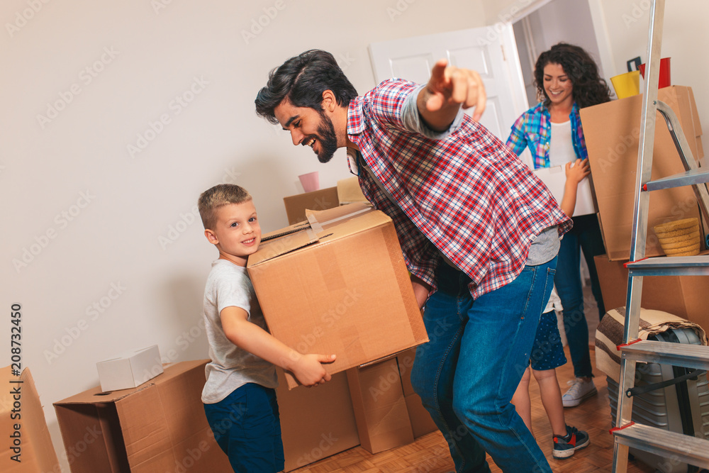 Wall mural Happy young family moving into their new home.	They carrying boxes into the apartment.