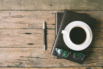 cup of coffee with glasses and book on wooden table