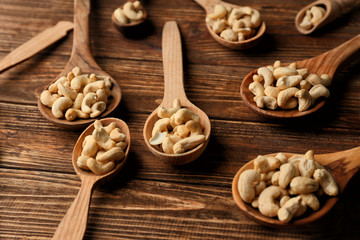 Spoons with tasty cashew nuts on wooden table