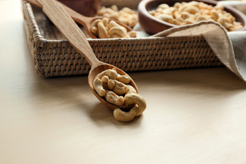 Spoon with tasty cashew nuts on wooden table
