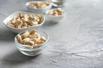 Bowls with tasty cashew nuts on light background