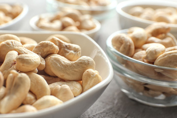 Bowls with tasty cashew nuts on table, closeup
