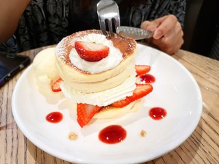  Women eating strawberry pancakes with icing ,whipping cream and ice cream vanilla on wooden background.
