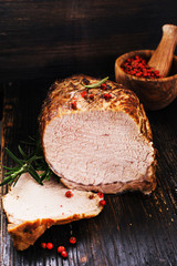 Roasted shoulder with rosemary and spices on a black wooden cutting board