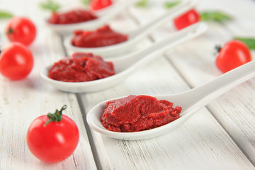 Delicious red sauce in ceramic spoons on table